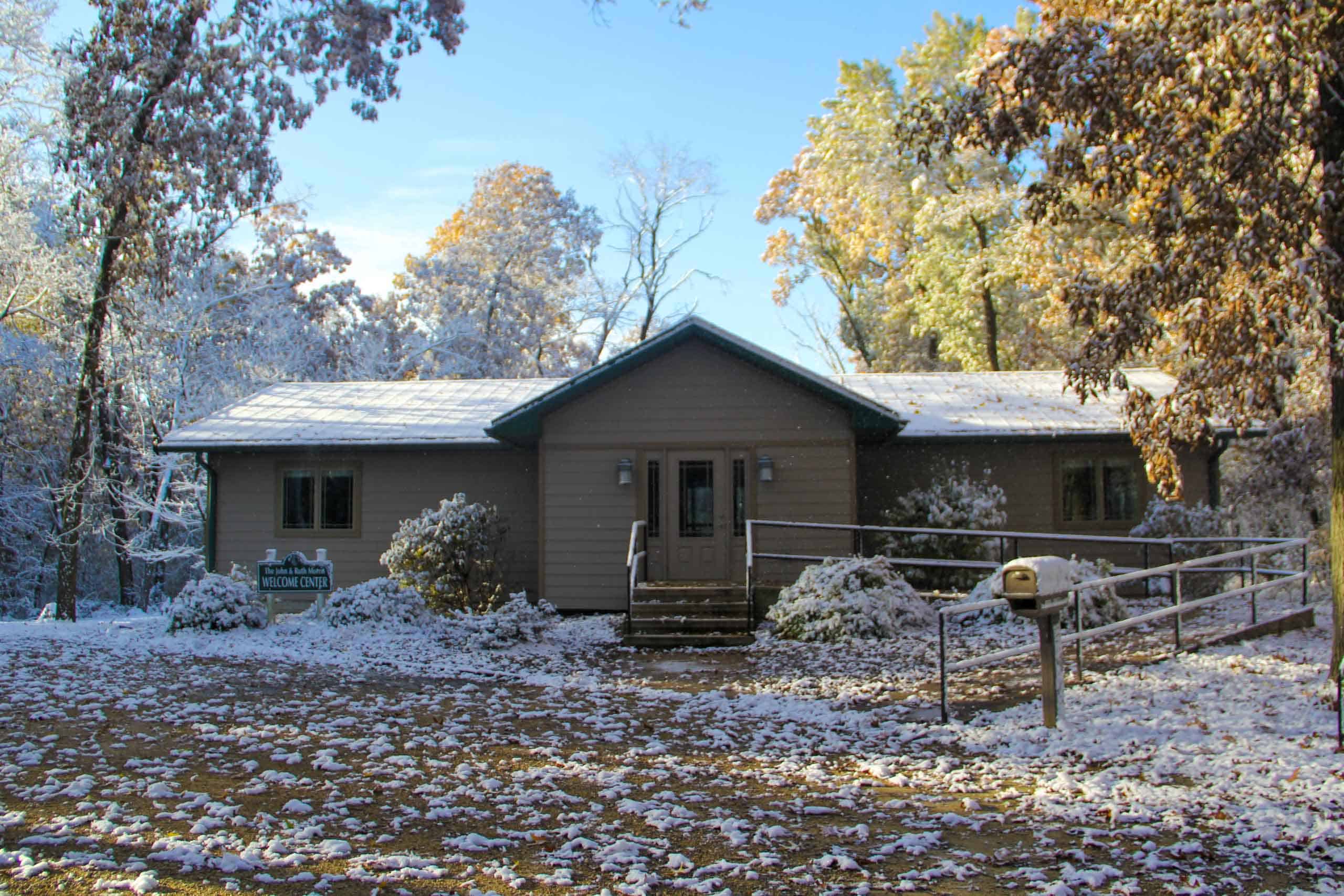 A summer camp cabin in the woods of Iowa during winter, covered in snow.